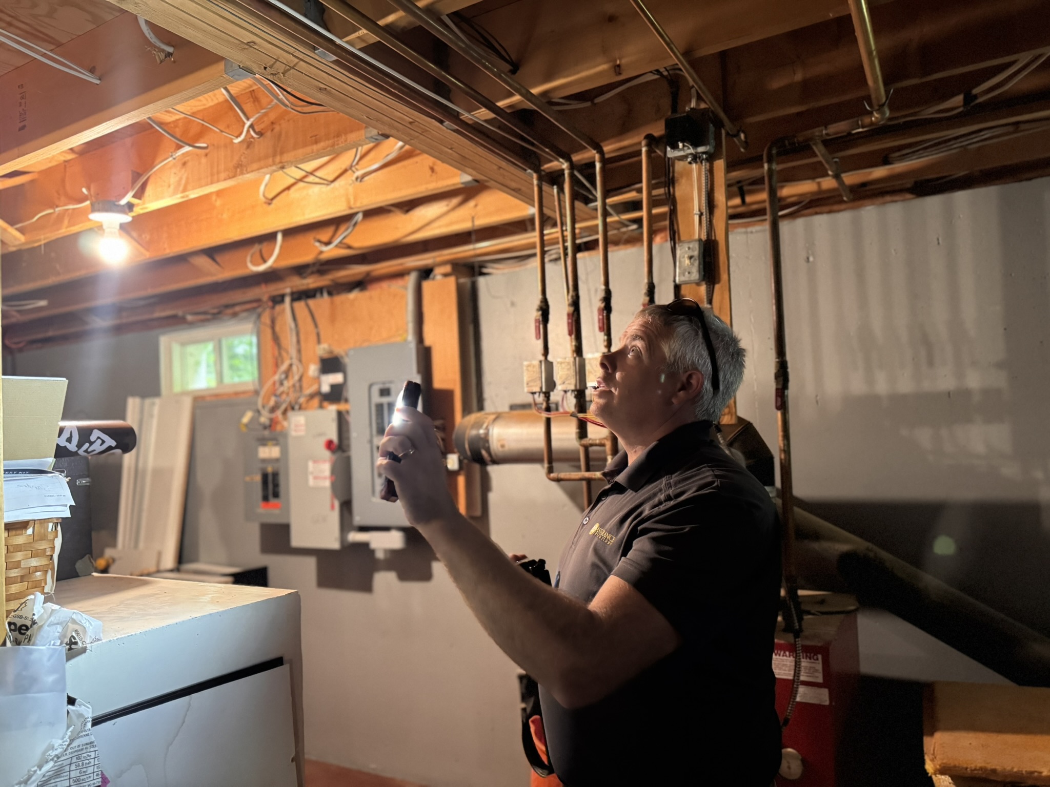 Professional home inspector examining HVAC systems in basement with inspection equipment