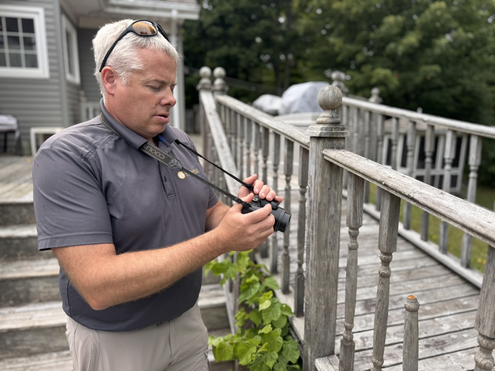 Professional home inspector using thermal imaging equipment on wooden deck